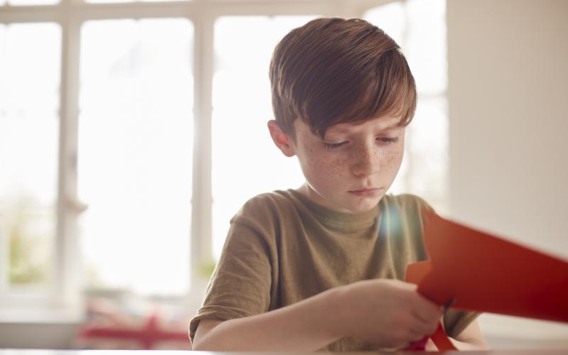 En dreng klipper i et orange papir